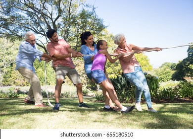 Smiling family playing tug of war in the park - Powered by Shutterstock