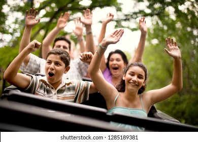 Smiling Family Riding On A Rollercoaster At An Amusement Park.