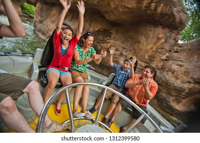 Smiling Family Riding On A Water Ride At An Amusement Park.