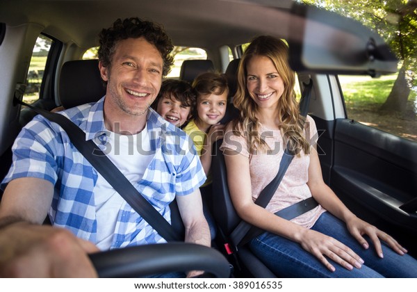 Smiling family\
sitting in the car and\
driving