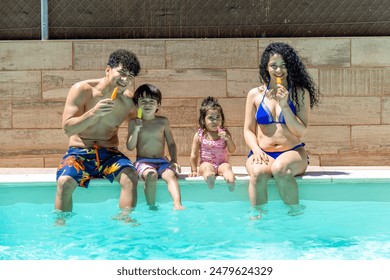 Smiling family sitting at the edge of a pool, enjoying colorful popsicles together on a sunny summer day, creating a happy and refreshing moment - Powered by Shutterstock