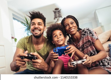 Smiling family sitting on the couch together playing video games
