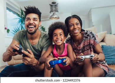 Smiling family sitting on the couch together playing video games - Powered by Shutterstock