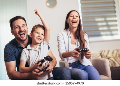 Smiling Family Sitting On The Couch Together Playing Video Games