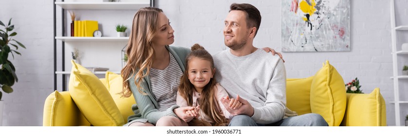 Smiling Family Sitting On Yellow Couch At Home, Banner