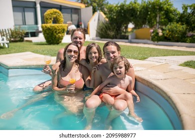 Smiling Family In Swimming Pool At Backyard. Cute Boys Of Different Ages And Mid Adult Parents Looking At Camera, Smiling, Making Faces. Leisure, Family, Party Concept