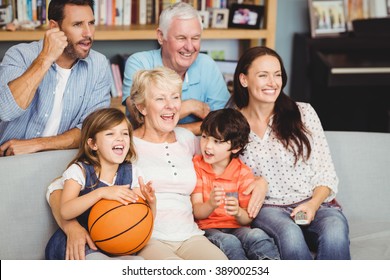 Smiling Family Watching Basketball Match At Home