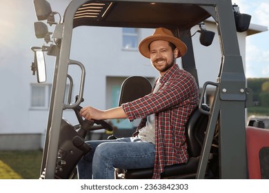 Smiling farmer driving loader outdoors. Agriculture equipment - Powered by Shutterstock