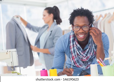 Smiling fashion designer on the phone in a bright studio - Powered by Shutterstock