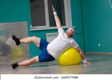 Smiling fat man is doing exercises using fitness ball. Overweight man is happy with the result of his training in group fitness classes