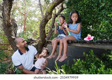 Smiling father assisting daughters and son blowing bubbles on tree - Powered by Shutterstock