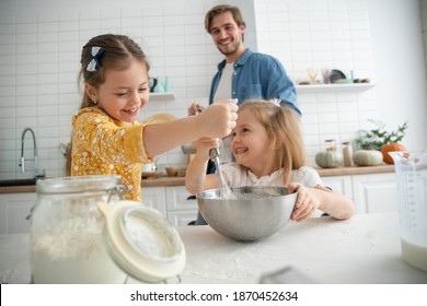 smiling father and daughters baking in the kitchen and having fun - Shutterstock ID 1870452634