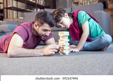 Smiling Father And Focused Son Playing Jenga Game At Home