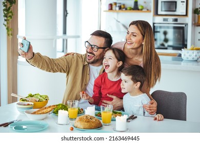 Smiling father holding cellphone, making selfie shot, recording video with happy wife and little kids siblings. Excited parents looking at mobile screen with kids, feeling excited. - Powered by Shutterstock