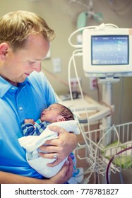 Smiling Father Holding His Newborn Baby Son In A Hospital Room