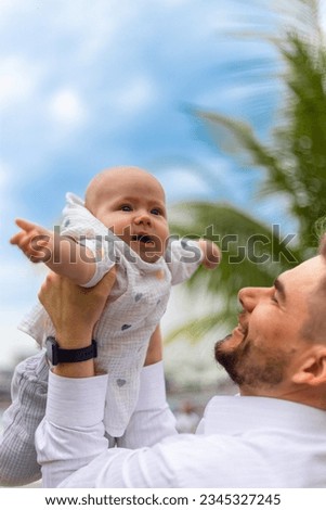 Smiling father holds a happy baby in his arms