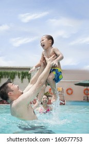 Smiling Father Lifting His Son Out Of The Water