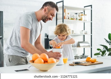 smiling father and little son making fresh orange juice by squeezer on table at kitchen  - Powered by Shutterstock