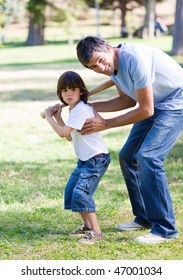 Smiling Father Playing Baseball With His Son In The Park