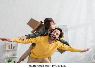 Smiling father playing with on in aviator helmet and wings - Powered by Shutterstock