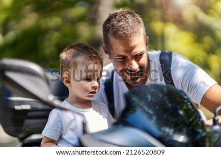 A smiling father showing commands on motorcycle to his son.