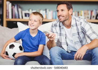 Smiling Father And Son Watching Football Match At Home