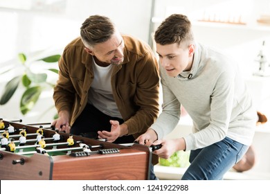 Smiling Father And Teen Son Playing Table Football At Home