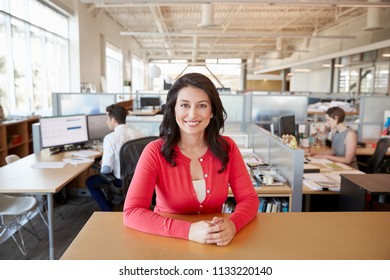 Smiling female architect at a desk in busy open plan office - Shutterstock ID 1133220140