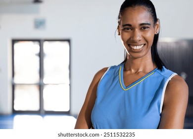 Smiling female basketball player in blue jersey posing confidently in gym. Athlete, sports, confidence, fitness, uniform, competition - Powered by Shutterstock