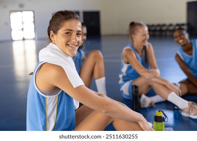 Smiling female basketball players sitting on court, resting after practice. Sports, teamwork, athletes, relaxation, fitness, gym - Powered by Shutterstock