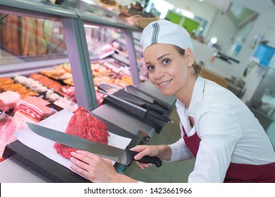 smiling female butcher cutting meat - Powered by Shutterstock