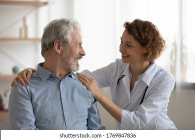 Smiling Female Caregiver Comfort Support Sick Senior Male Patient In Retirement House, Happy Caring Woman Doctor Or Nurse Touch Talk Give Help To Ill Weak Mature Man In Hospital, Healthcare Concept