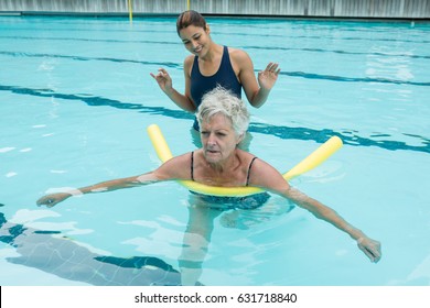 Smiling female coach helping senior woman in swimming pool - Powered by Shutterstock