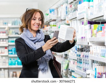 Smiling Female Customer Scanning Product Through Mobile Phone In Pharmacy