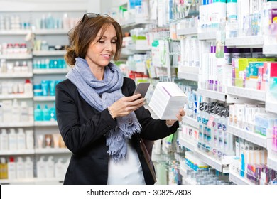 Smiling Female Customer Scanning Product Through Cell Phone In Pharmacy