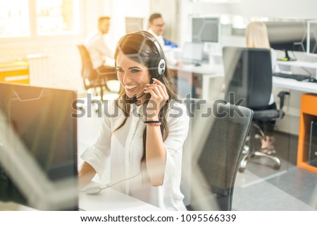 Smiling female customer support operator with headset working in office