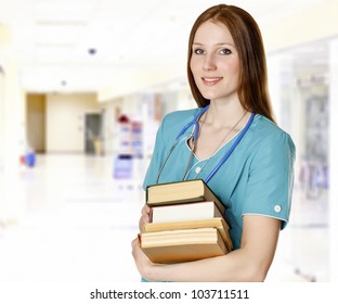 Smiling Female Doctor With Books In A Hall Of A Hospital