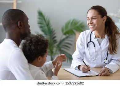 Smiling Female Doctor Consult African American Dad With Little Boy Patient Write Prescription In Medical Card, Happy Positive Woman Pediatrician Talk With Biracial Father With Son Visiting Hospital