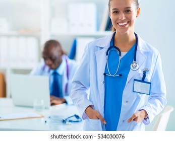 A smiling female doctor with a folder in uniform indoors - Shutterstock ID 534030076