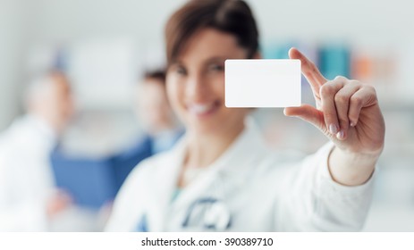 Smiling female doctor holding a blank business card, selective focus, business and healthcare concept - Powered by Shutterstock