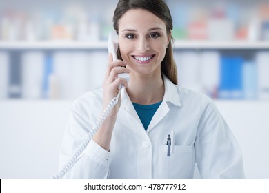 Smiling female doctor holding a receiver and answering phone calls, medical service