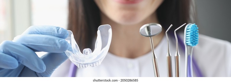 Smiling Female Doctor Holds Transparent Plastic Mouth Guard And Stomatological Instruments In Her Hand