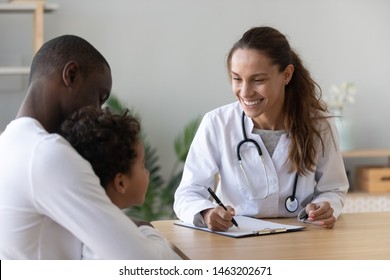 Smiling female doctor listen consult cute african boy make notes in patient card at medical checkup appointment, black dad and child son visit pediatrician talk in clinic, children healthcare concept