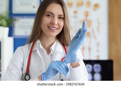 Smiling Female Doctor Putting On Medical Gloves