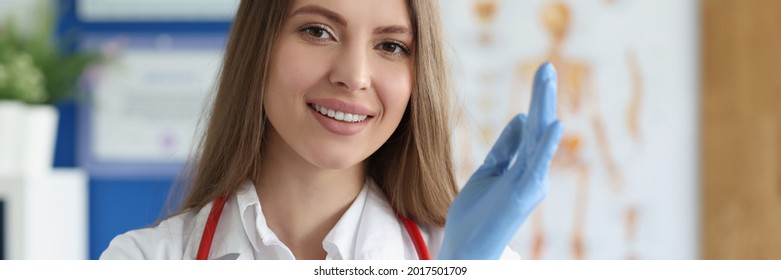 Smiling Female Doctor Putting On Medical Gloves