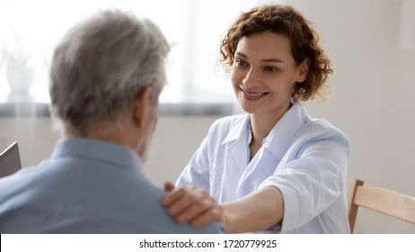 Smiling female doctor reassuring supporting senior adult patient in hospital. Kind caring young woman nurse or caregiver helping older retired man talking, giving comfort, expressing care concept. - Powered by Shutterstock