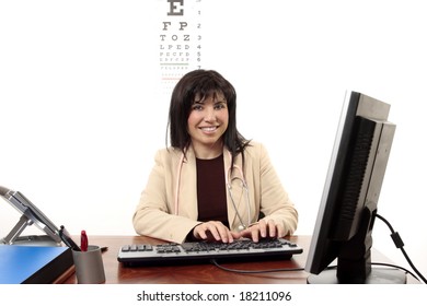 Smiling Female Doctor Sitting At Desk And Using Computer.