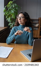 Smiling female employee at workplace, looking in window, businesswoman resting from computer work, being satisfied with job. Happy woman office worker wearing glasses dreaming during work time