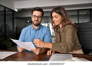 Smiling female financial advisor, attorney lawyer or bank manager consulting client investor reading document at business meeting reviewing legal paper file planning taxes working in office.
