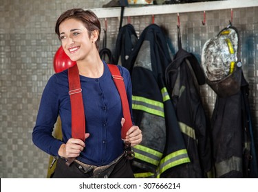 Smiling Female Firefighter Looking Away While Standing At Fire Station